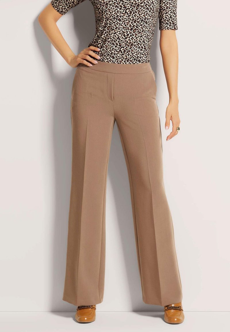 Beige wijde broek met een gladde textuur, met voorplooien, gedragen met een zwart en tan luipaardprint top en tan schoenen.