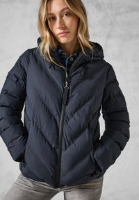 Veste matelassée bleu marine avec motif en chevrons, capuche amovible et fermeture éclair. Fabriquée en tissu lisse et isolant. Fermeture éclair noire contrastante.