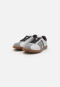 Kerged sneakersid halli ja valge nahast ja sametisest pealiskattega, mustade nööride ja pruuni kummitaldaga.
