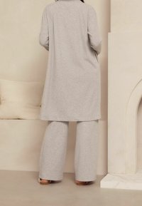 Lichtgrijze, lange mouw tuniek met een rechte snit, in combinatie met wijde broek, beide gemaakt van zachte, gestructureerde stof. Eenvoudig en minimalistisch ontwerp.