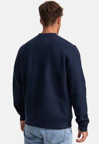 Suéter texturizado azul marino con un diseño de canalé, cuello redondo y banda inferior en contraste. Presenta mangas largas y puños elásticos.