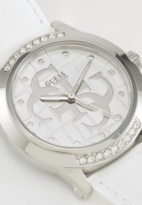 Orologio argentato con cinturino in pelle bianca, caratterizzato da un quadrante bianco lucido con un motivo testurizzato, dettagli argentati e decorazioni in cristallo.
