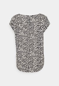 Blouse noir et blanc à manches courtes avec un imprimé léopard abstrait et une fermeture éclair visible au dos.