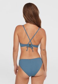 Bikini blu con spalline incrociate regolabili, chiusura annodata e una texture liscia e opaca. Presenta un design semplice e classico con hardware minimal.