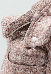 Geantă cu model floral, din țesătură bej deschis și albă. Are un sistem de închidere cu fermoar, un accent cu bătușă și un buzunar, evidențiind o textură matlasată.