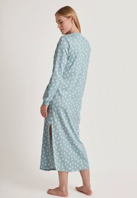 Langarm-nachtjapon van lichtblauwe stof met een hartpatroon. Het ontwerp heeft een zijsplit en een rechte zoom.