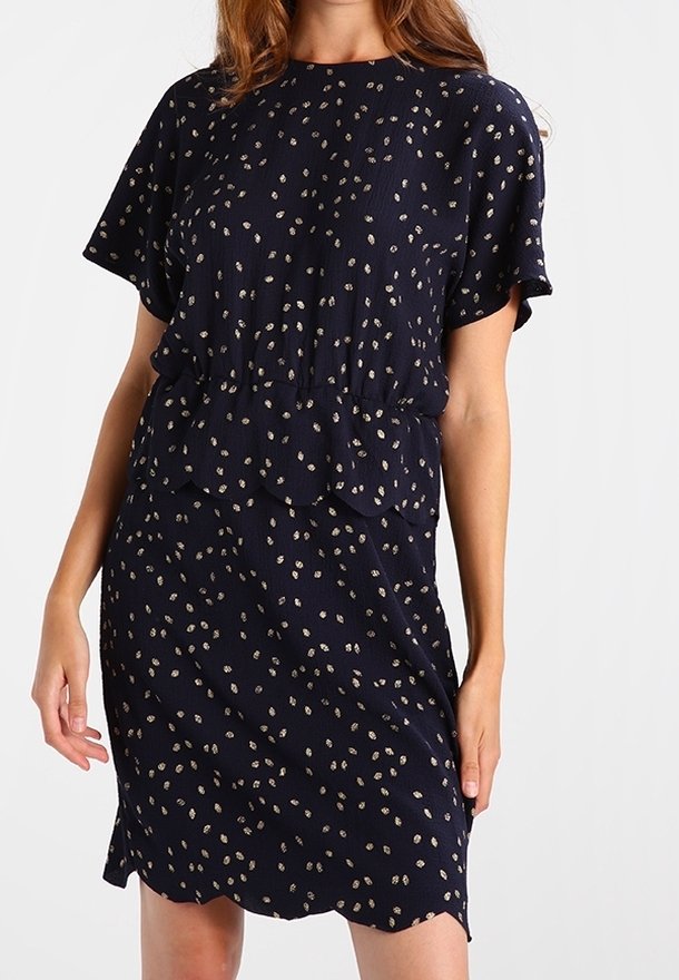 Robe bleu marine à manches courtes, taille peplum et motif à pois dorés. Tissu doux avec un ourlet festonné, offrant une apparence texturée.