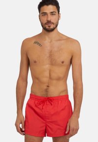 Bañador rojo con cintura elástica y cordón. Fabricado con un tejido ligero, presenta una textura suave y un diseño sencillo.