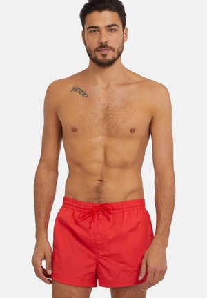 Bañador rojo con cintura elástica y cordón. Fabricado con un tejido ligero, presenta una textura suave y un diseño sencillo.