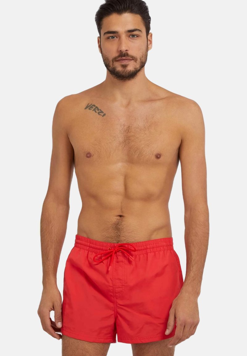 Bañador rojo con cintura elástica y cordón. Fabricado con un tejido ligero, presenta una textura suave y un diseño sencillo.