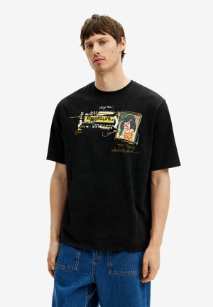 Zwarte katoenen T-shirt met een grafisch ontwerp aan de voorkant met tekst, kleurrijke accenten en een relaxte pasvorm. In combinatie met blauwe spijkerbroek.