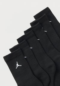 Seis pares de calcetines negros tipo crew con el logo blanco de Jumpman alineados en diagonal sobre un fondo claro.