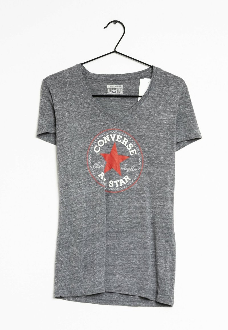 Camiseta gris de manga corta y escote en V, hecha de una suave tela texturizada. Presenta un gráfico circular en rojo y blanco con una estrella y el texto "Converse All-Star".