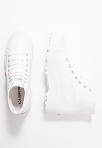 Sneaker alte in tela bianca con punta rotonda, tessuto testurizzato e occhielli in argento. Suola in gomma bianca spessa con motivo di aderenza.