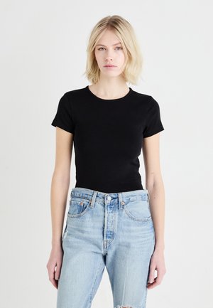 T-shirt noir en coton à manches courtes et col rond, associé à un jean taille haute déchiré bleu clair. Design simple et ajusté.