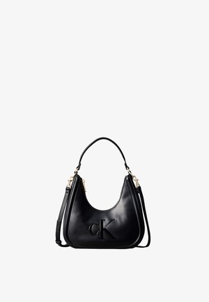 Sac à main en cuir noir avec logo « cK » embossé, doté d’une poignée courte et d’une bandoulière amovible avec des ferrures dorées.