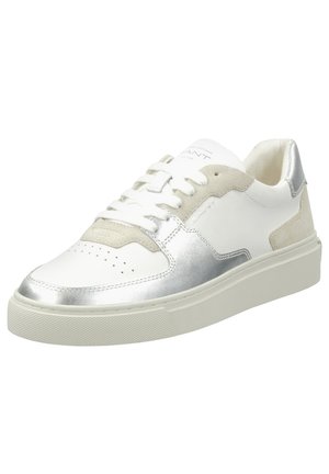 Weiße Sneaker mit silbernen Akzenten, Wildlederdetails, perforiertem Zehenbereich, runden Schnürsenkeln und einer strukturierten Gummisohle. Branding auf der Zunge sichtbar.