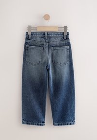 Traperice s tamnoplavim pranjem, srednjim strukom i dizajnom s pet džepova. Imaju podvrnute rubove i petlju za vješanje.