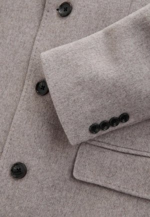 Hellgrauer Wollmantel mit Schößchenkragen, vier schwarzen Knöpfen an den Ärmeln und einer weichen, strukturierten Oberflächenausführung.