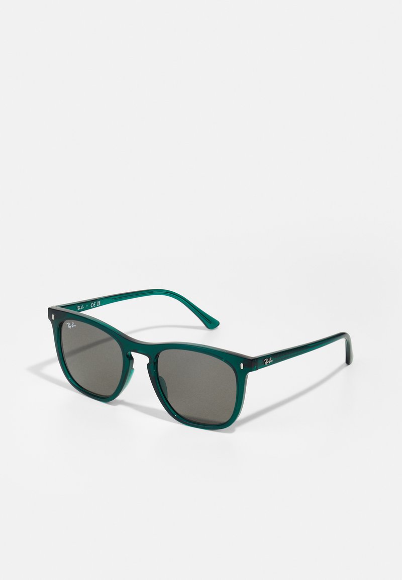 Ochelari de soare cu ramă din plastic verde, lentile pătrate, sticlă tintată de un gri închis, accent de logo argintiu pe brate și brațe late, netede.