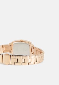 Rose guld metal armbåndsur med firkantet urkasse, en poleret bagside og et linked armbåndsdesign med en spænde-lukning.