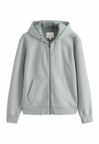 Hoodie gris clair en tissu doux, avec fermeture éclair, poches avant et capuche à cordon de serrage. Texture douce avec un tissu côtelé aux poignets.