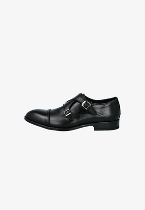 Zapato formal de cuero negro con hebillas de doble correa monk y un tacón bajo, mostrado de perfil sobre un fondo blanco.