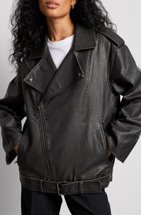 Schwarze Motorradjacke aus Kunstleder mit breitem Revers, Reißverschluss und Gürtelschlaufen in der Taille. Mit seitlichen Taschen und sichtbaren Nähten.
