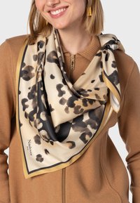 Silk tørklæde med en beige bund og sort og brun leopardprint, kantet med en solid guldkant, draperet elegant.