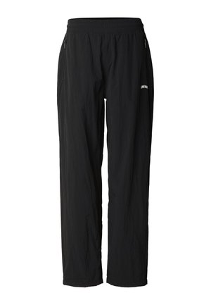 Czarne casualowe spodnie z elastycznym pasem, przednimi kieszeniami na zamek oraz małym białym logo "UNFAIR" na lewej udzie.