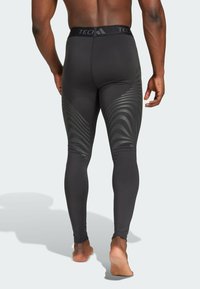 Schwarze Sportleggings mit engem Sitz, die an den Seiten ein strukturiertes Muster in Dunkelgrau und einen markierten Bund aufweisen.