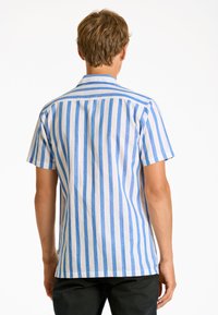 Camisetta a maniche corte a righe verticali blu e bianche. Realizzata in tessuto leggero con colletto e design a taglio dritto.