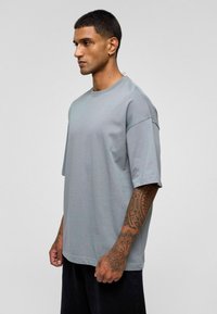 Lichtgrijs oversized t-shirt met korte mouwen, gemaakt van een zachte stof. Heeft een ronde halslijn en een casual pasvorm.