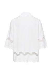 Blouse blanche à manches trois-quarts, avec une bordure en dentelle et une broderie florale le long des manches et de l'ourlet, vue de dos.