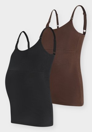 Femme enceinte debout portant un débardeur marron moulant et un legging, un grand sac à bandoulière marron, des sandales noires et un bracelet doré.