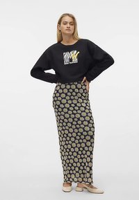 Black sweatshirt with graphic print paired with a long, fitted skirt featuring a white daisy pattern on a black background. Smooth texture.