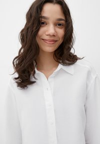 Witte button-up shirt met een kraaghalslijn, gemaakt van een textuurstof, met lange mouwen en subtiele stiksels.