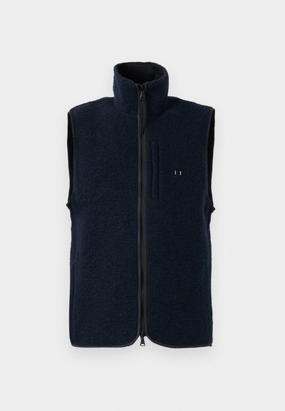 Granatowa kamizelka polarowa z wysokim kołnierzem, pełnym zamkiem błyskawicznym i przednią kieszenią. Teksturowana powierzchnia oraz kontrastowa podszewka.