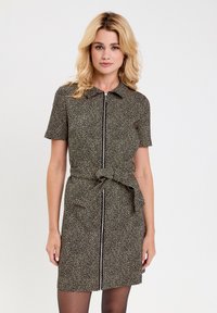 Robe à manches courtes en noir avec un subtil motif animal, dotée d'une fermeture éclair devant et d'une ceinture en tissu, fabriquée dans un matériau léger.