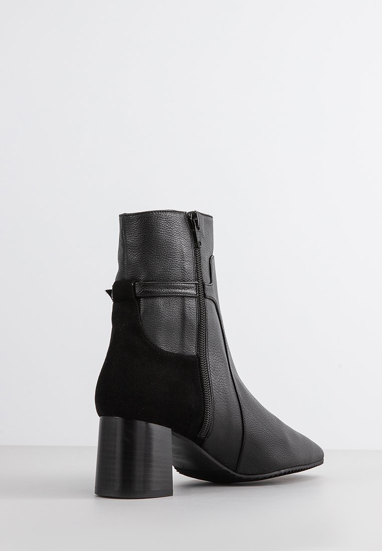 Zwarte enkellaars met een spitse neus, een combinatie van gestructureerd leer en suède, zijritsdetail en een chunky hak.