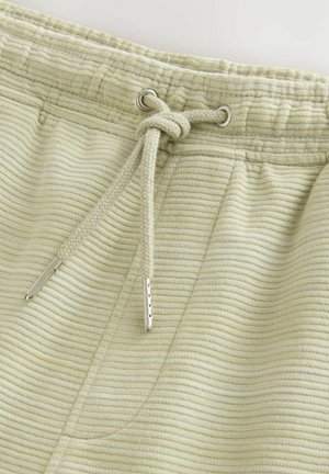 Lysgrønne sweatpants med en struktureret, ribbet stof. Har en elastisk talje med snoretræk og en enkelt sidelomme.