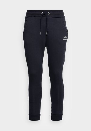 Navy cotton sweatpants with a drawstring waistband, side pockets, and ribbed cuffs; features a white logo on the left pocket.