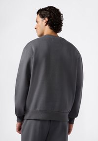 Grijze sweater met een ronde halslijn en geribbelde zoom. Gemaakt van een zacht materiaal, met een relaxte pasvorm en minimalistisch ontwerp.