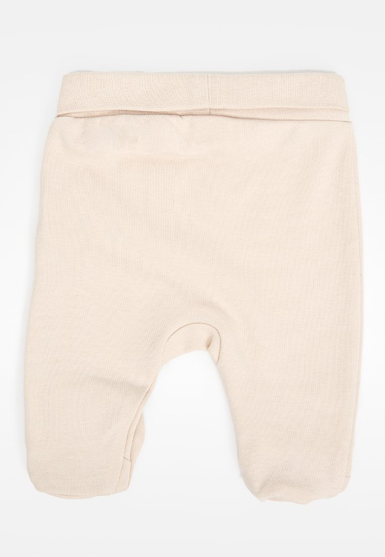 Pantalones de bebé de un suave tono beige con cinturilla elástica doblada y pies cerrados, hechos de tejido de punto acanalado, dispuestos sobre un fondo blanco.