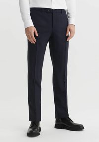 Granatowe, dopasowane spodnie w kratę, wykonane z gładkiego materiału, z płaskim przodem i slim fit, w zestawieniu z czarnymi butami na sznurówki.