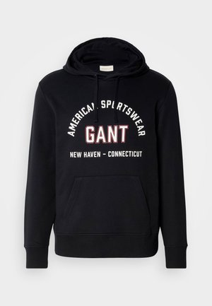 Hoodie preto feito de algodão, com um bolso canguru na frente e capuz com cordão. Design de texto ousado em branco e vermelho na parte da frente.