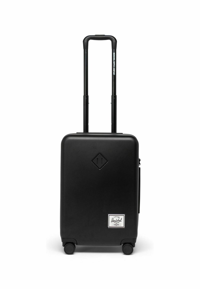 Valise rigide noire avec un logo en forme de diamant, deux roues en caoutchouc, une poignée extensible et une petite poche avant avec une étiquette.