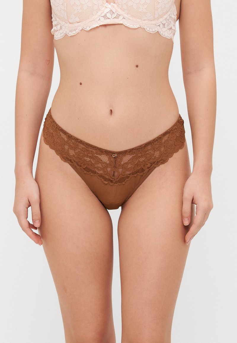 Hnědé krajkové tanga s květinovým vzorem na pase, s hladkým, průhledným tělem a malým detailem uprostřed.