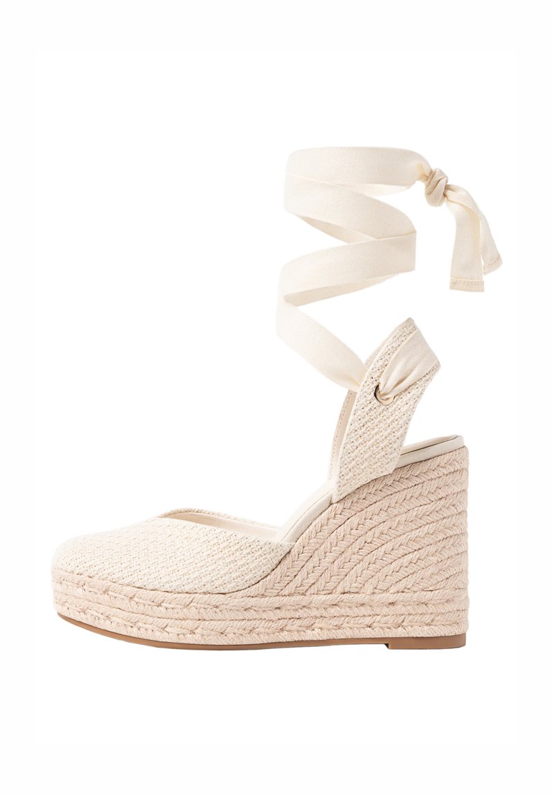 Espadrille compensée beige tissée avec ruban à nouer à la cheville et bout fermé, dotée d'une semelle en jute texturée et d'une tige en tissu.