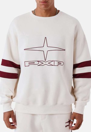 Homme portant un sweat-shirt blanc avec un logo étoile bordeaux et le texte "PXP", présentant des rayures bordeaux sur les manches.